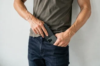 Homme essayant de glisser un grand iPhone dans la poche avant d'un jean slim, illustrant les problèmes de dimensions de l'iPhone 15 Plus